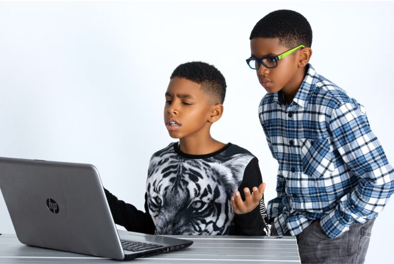 Two children using an HP laptop against a white background