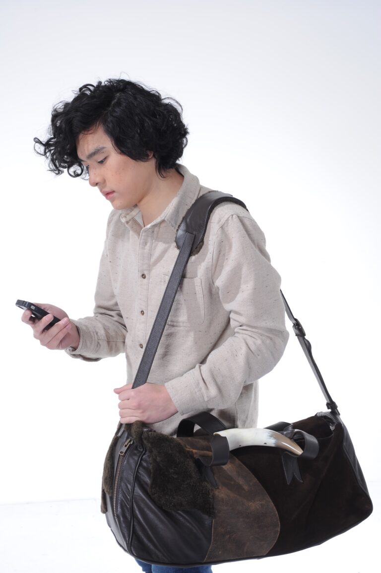 Man carrying a brown bag and looking at his phone