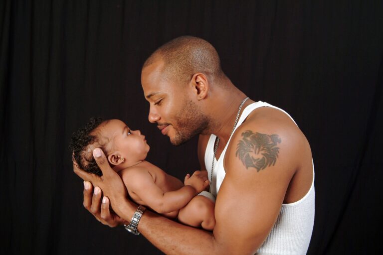 Father holding a newborn against a black background