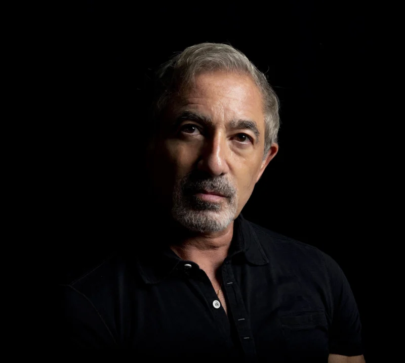 Dramatically lit studio portrait of a man against a dark background