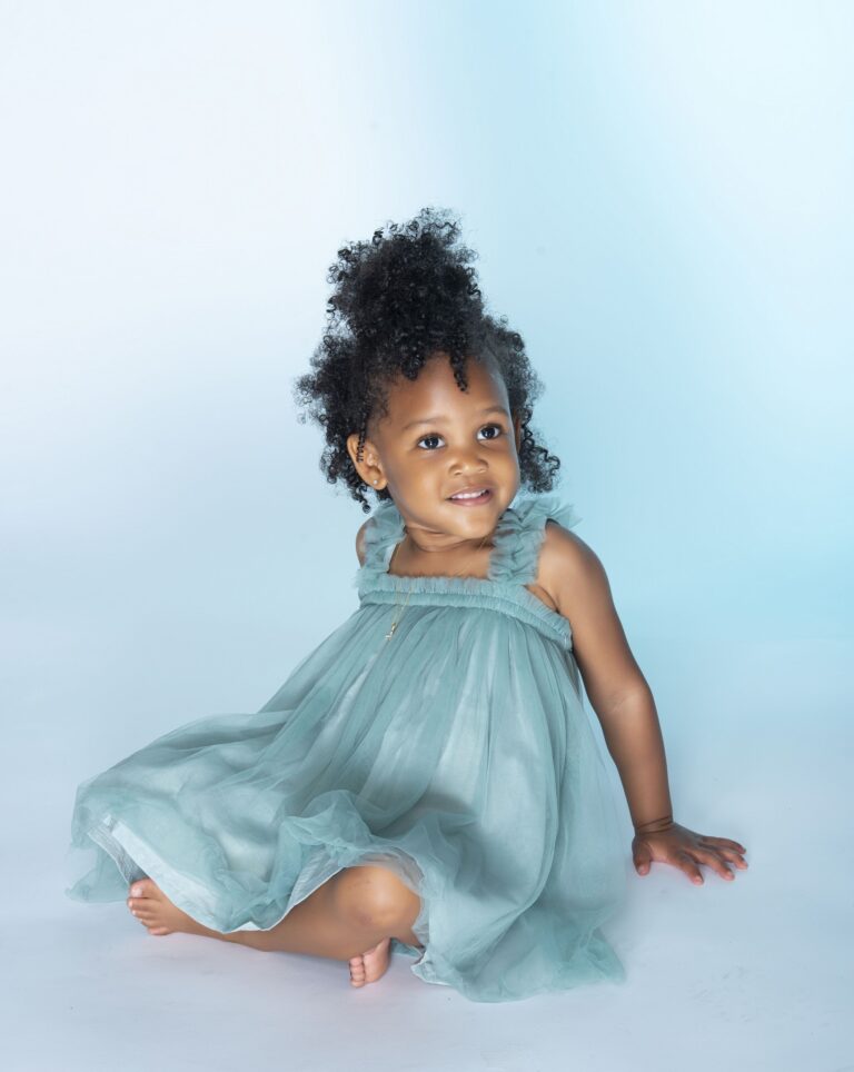 Little girl in a blue dress posing in a studio