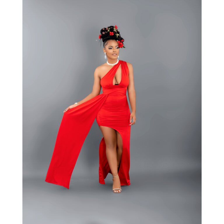 Woman in a red floor-length dress against a gray studio backdrop
