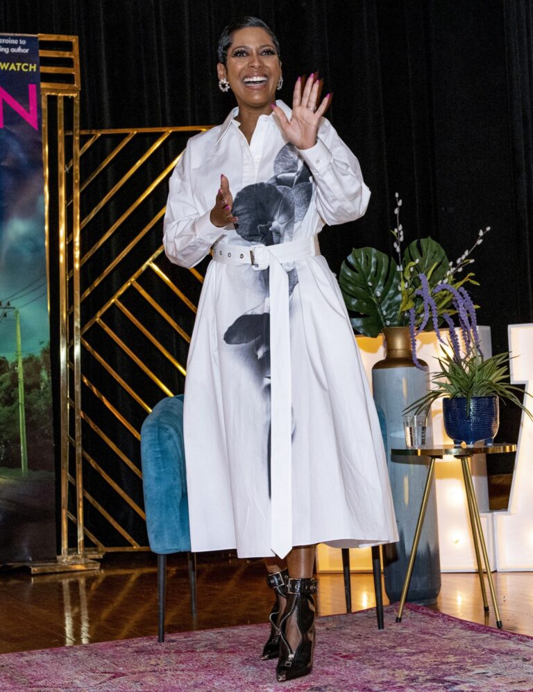 Woman in a white outfit speaking into a microphone onstage