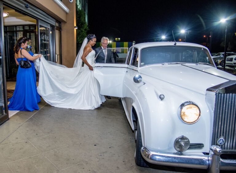 Bride beside a white classic car at night