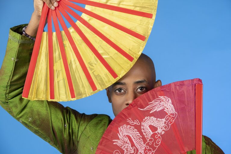Child holding colorful fans in a staged portrait against a blue background