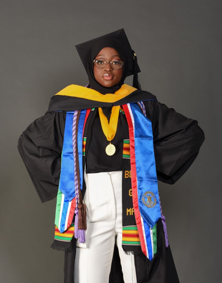 Woman in a black graduation cap and gown with a colorful stole