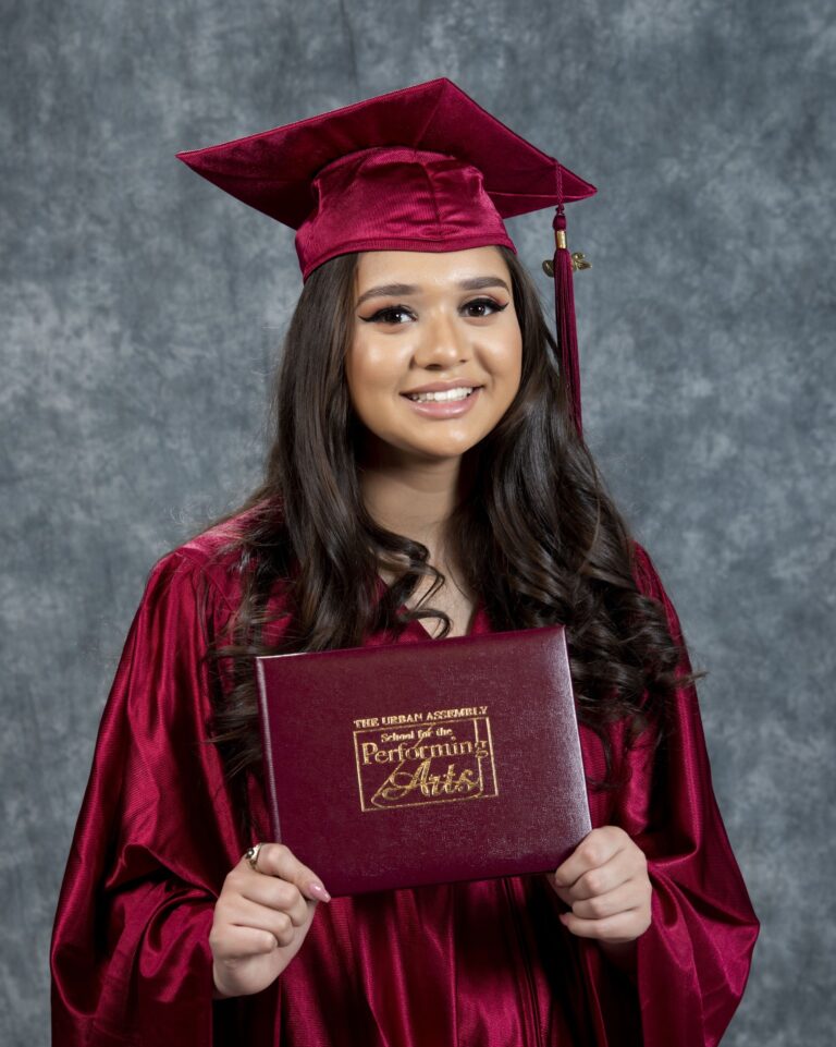 Woman in a burgundy graduation cap and gown holding a certificate
