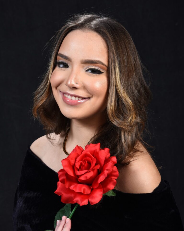Young woman in black with draped red roses in a studio portrait