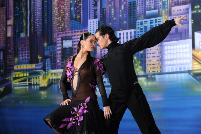 Two dancers performing against a city-scene stage backdrop
