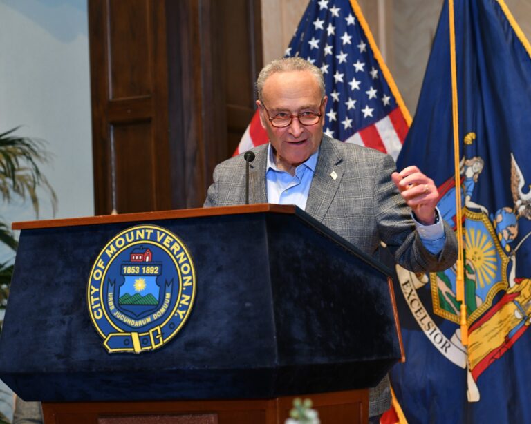 Man speaking at a lectern with U.S. flags behind him