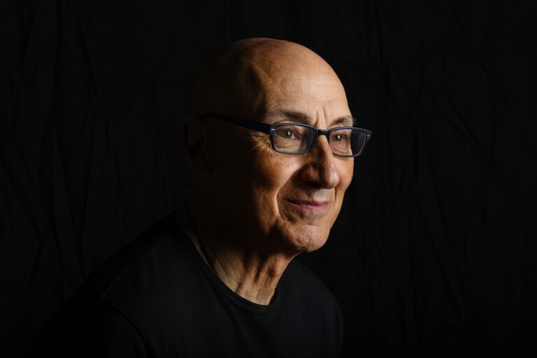 Side-lit smiling man in glasses looking off camera