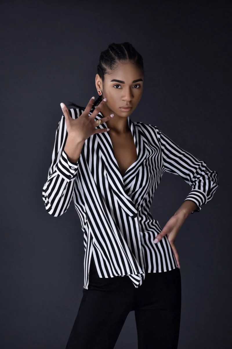 Studio portrait of a woman posing in a black-and-white striped blouse