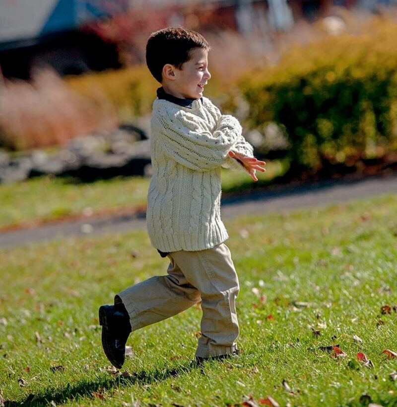 Outdoor portrait of a child running across a sunny lawn