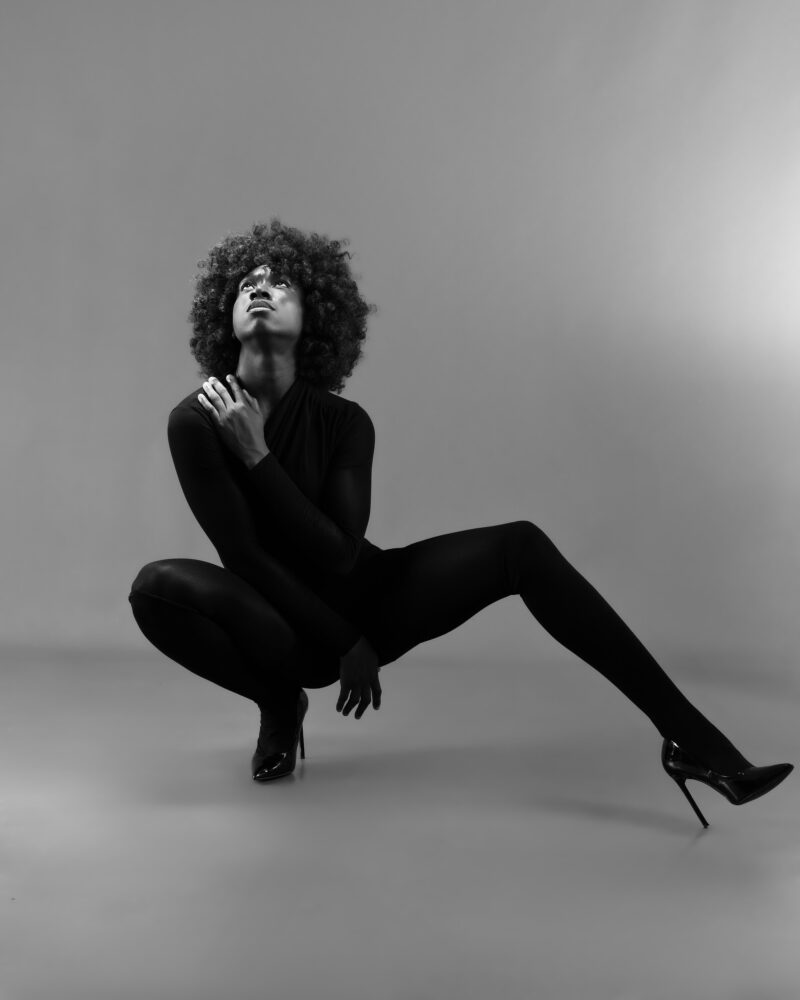 Monochrome studio portrait in a low pose with one leg extended