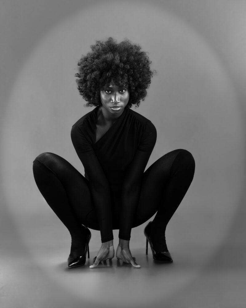 Monochrome studio portrait in a low crouching pose