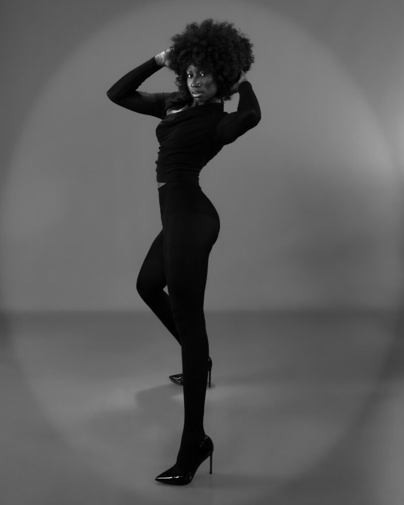 Standing monochrome fashion portrait with hands framing the hair
