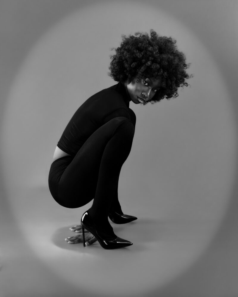 Monochrome studio portrait curled into a crouching pose