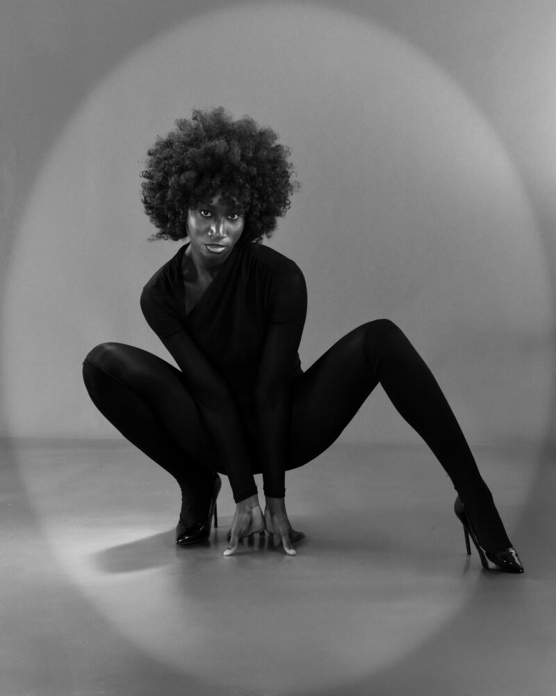Monochrome studio portrait crouching with one leg extended