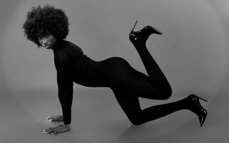 Monochrome landscape studio portrait in a dynamic floor pose with bent legs