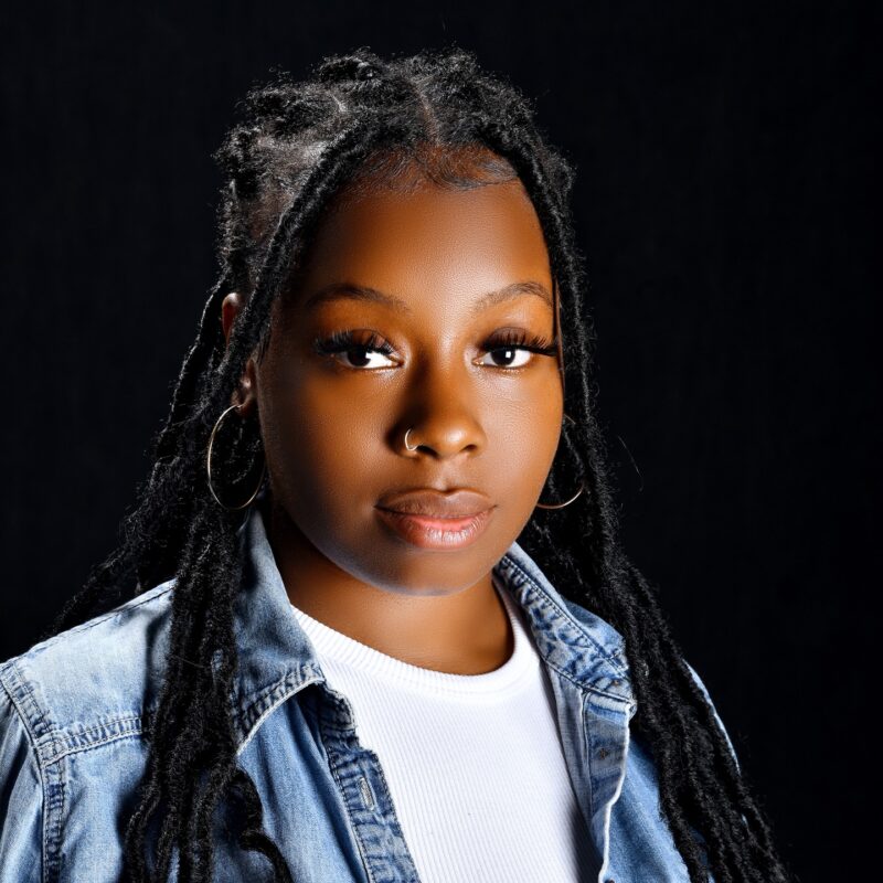 Studio portrait of a girl in a denim shirt against a dark background