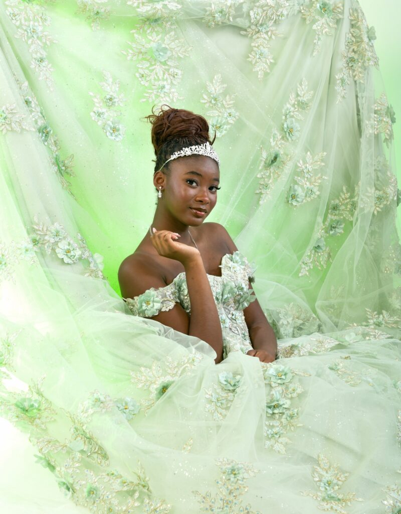 Studio portrait surrounded by the fabric of a pale green gown